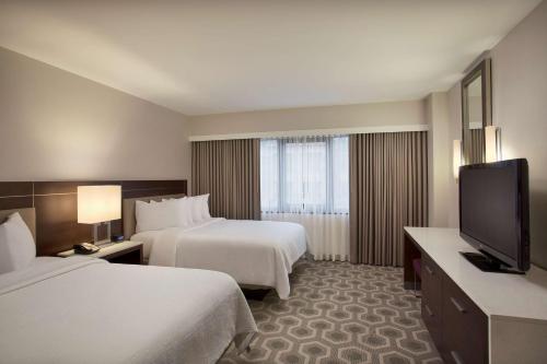 华盛顿华盛顿特区乔治敦希尔顿合博套房酒店的酒店客房设有两张床和一台平面电视。