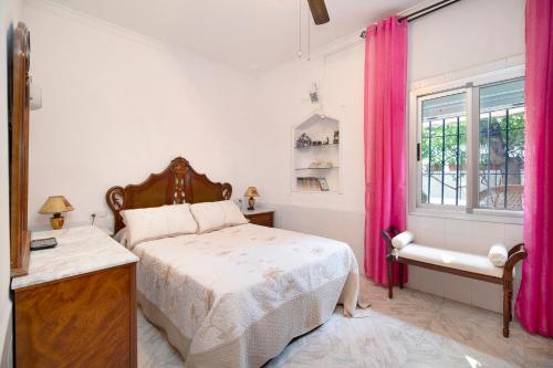 赫雷斯-德拉弗龙特拉Casa Catalina的一间卧室配有床和一个带粉红色窗帘的窗户。