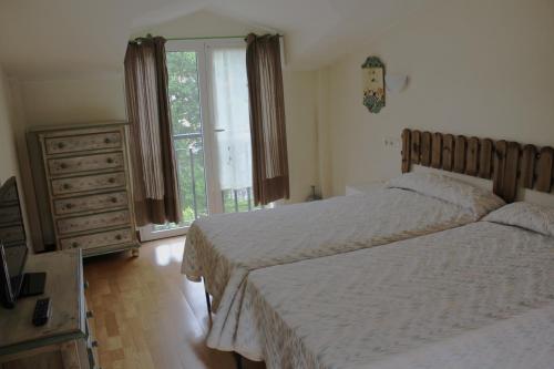 IcazteguietaIkaztegietako Ostatua的一间卧室设有两张床、一个梳妆台和窗户。