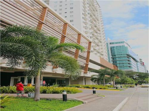 宿务1-BR unit in IT Park Cebu City的骑着自行车穿过棕榈树的建筑的人