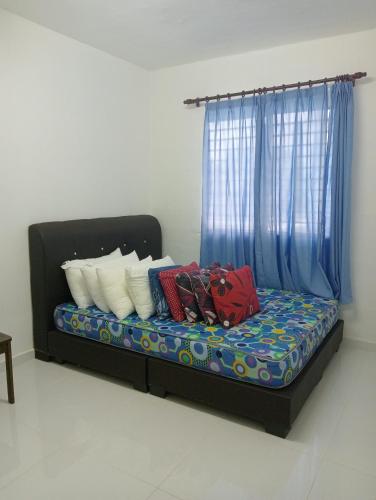 万挠SERI BAKAWALI HOMESTAY的一张带蓝色窗帘的床和一些枕头
