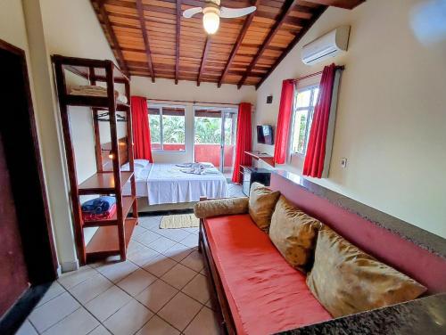 乌巴图巴卡萨纳普拉亚旅馆 的客厅配有红色的沙发和床。