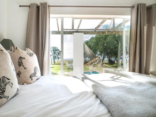 格拉罕镇Land's End Private Game Reserve的一张带白色床单和枕头的床,位于窗户前