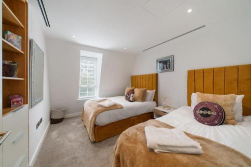 伦敦Marble Arch Penthouse 3 Bed的配有白色墙壁的小客房内的两张床