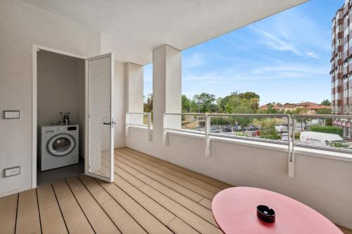 米兰limehome Milan via Stresa的阳台配有洗衣机和粉红色的桌子。