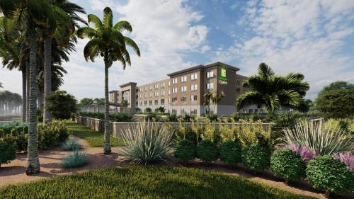 卡纳维拉尔角Holiday Inn Express Cape Canaveral, an IHG Hotel的花园中种有棕榈树和植物的酒店