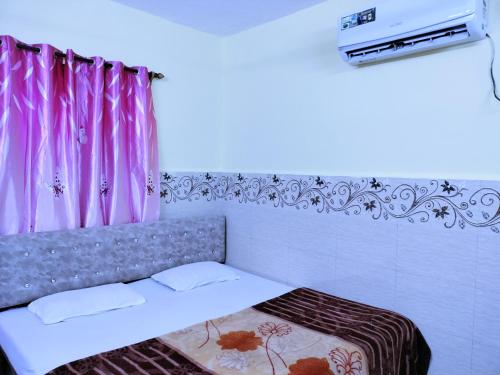 科尔瓦Beach Xaviers Guest House Colva的一间卧室配有一张带粉红色窗帘的床