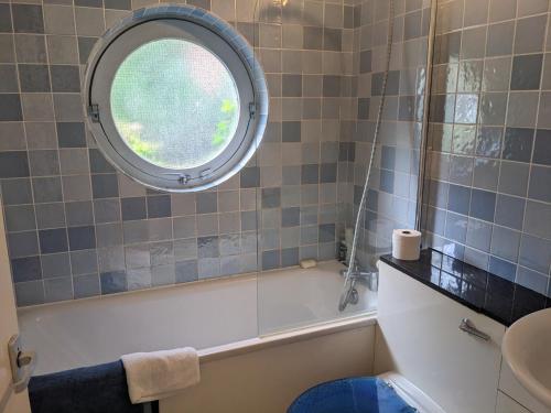 伦敦Rotherhithe apartment near park and river的带浴缸的浴室和圆形窗户。