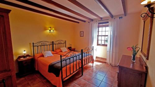 Los SaucesLos Nacientes: Cordero的一间卧室配有带橙色床单的床和窗户。