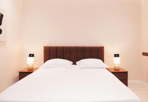 地拉那Mono Boutique Apartments的一间卧室配有一张带两盏灯的大型白色床。