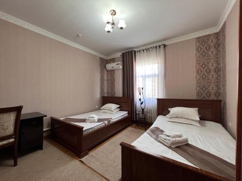 努库斯MASSAGET HOTEL的一间卧室设有两张床和窗户。