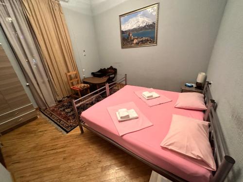 埃里温Bridge House Yerevan Armenia的小房间设有粉红色的床和两张桌子