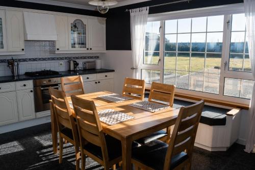 Atlantic views at Arnisdale House的厨房配有木桌、椅子和窗户。