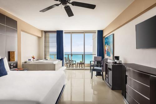 坎昆Seadust Cancun Family Resort - All Inclusive的一间卧室配有一张床,浴室设有浴缸