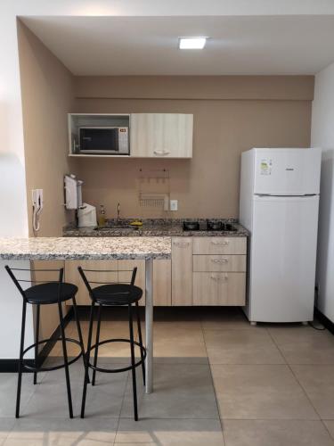 圣卡洛斯Spot Residence São Carlos 700m da USP的厨房配有桌子、两把椅子和冰箱