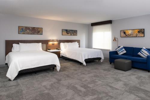 巴吞鲁日巴顿鲁日机场希尔顿花园酒店的酒店客房,设有两张床和一张蓝色的沙发
