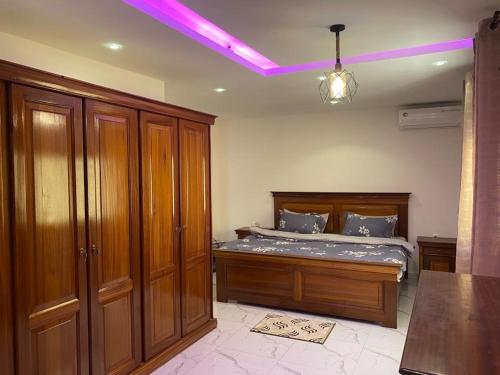萨利波图尔Villa OMARI Situé à Saly Portudal Villa 2 Chambres bien équipés proche de tout的一间卧室配有一张带木制家具和紫色灯的床。