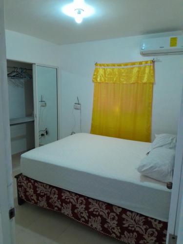圣地亚哥洛斯卡巴Comodo apartamento en el centro de la ciudad的小卧室配有一张黄色窗帘的床