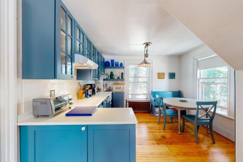 卡姆登The Bean House Upstairs and Downstairs Unit的厨房配有蓝色橱柜和桌椅