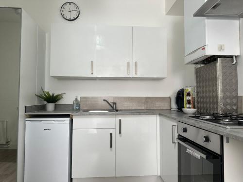 巴尔内特High Barnet Studio Flat的厨房配有白色橱柜和墙上的时钟