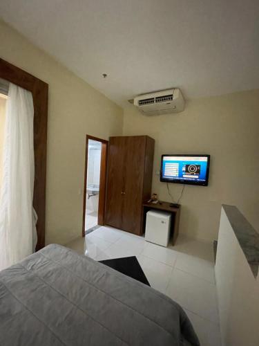 塔瓜汀加COBERTURA DUPLEX 70 m COM HIDRO NO MELHOR HOTEL DE TAGUATINGA的卧室配有一张床,墙上配有电视。