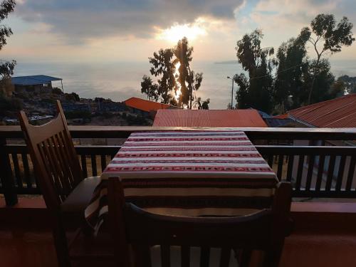 Comunidad YumaniHostal Quilla Wasi Isla del Sol的阳台配有桌椅,享有日落美景
