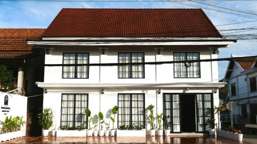琅勃拉邦Midnight Blue Guesthouse的白色的房子,设有黑窗和红色屋顶