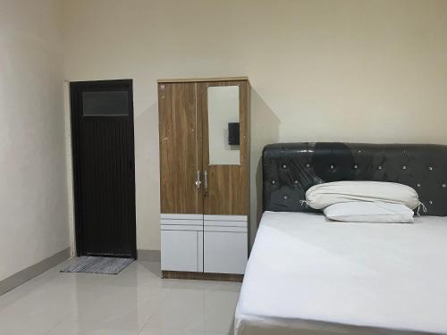 马卡萨SPOT ON 93022 Anugrah Homestay Syariah的一间卧室配有一张带黑色床头板和橱柜的床。