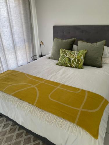SandtonFourways Luxe Suite的一张带黄色毯子和枕头的床