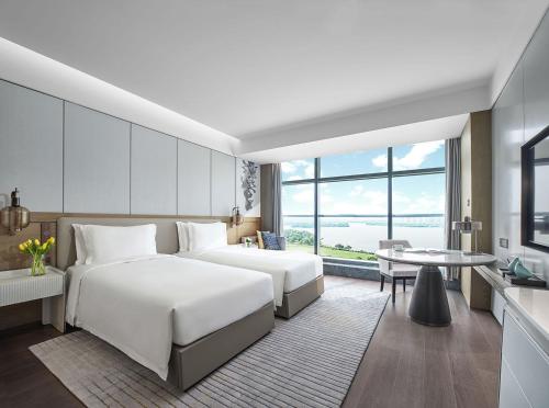 徐州徐州伊敦康得思酒店的酒店客房设有两张床和一张桌子。