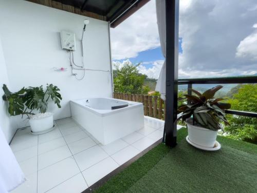 Mon JamPhu Fahsai Homestay的阳台上的白色浴室设有浴缸和植物