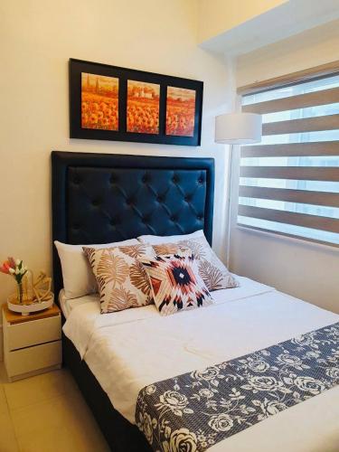 马尼拉1 Br CONDO Vine Residences Quezon City with POOL NETFLIX WIFI VIDEOKE BOARD GAMES的一间卧室配有一张蓝色床头板的床