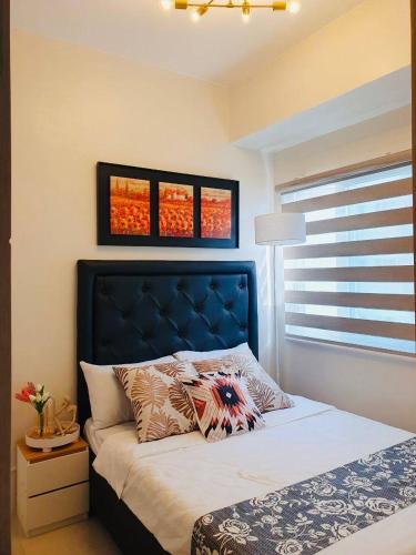马尼拉1 Br CONDO Vine Residences Quezon City with POOL NETFLIX WIFI VIDEOKE BOARD GAMES的一间卧室配有一张带蓝色床头板的床和窗户。