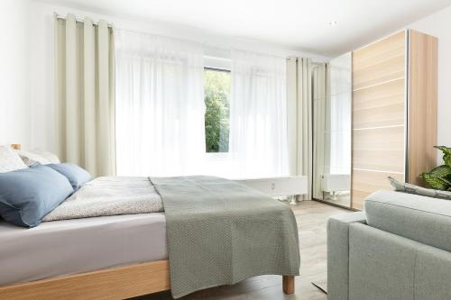 坡道旁盖斯林根Apart4me Scandi Apartment Geislingen zentral mit Parkplatz的一间卧室配有一张床、一张沙发和一个窗口