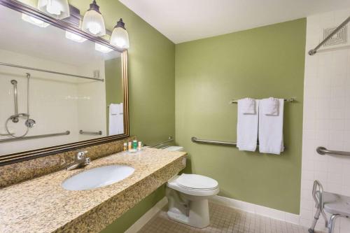 梅萨Days Inn & Suites by Wyndham Mesa Near Phoenix的一间带水槽、卫生间和镜子的浴室