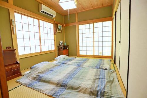 日光FOREST HOUSE NIKKO的带3扇窗户的客房内的一张大床