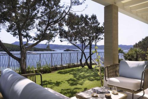 巴哈撒丁岛7Pines Resort Sardinia - A Destination By Hyatt的一个带椅子和桌子的门廊,享有水景