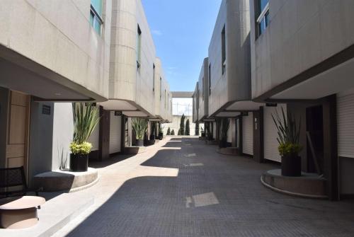 墨西哥城Ramada by Wyndham Mexico City Santa Fe的两座种植盆栽的建筑之间的空走廊