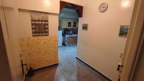 马拉喀什Résidence gharnata的走廊通往墙上带时钟的厨房