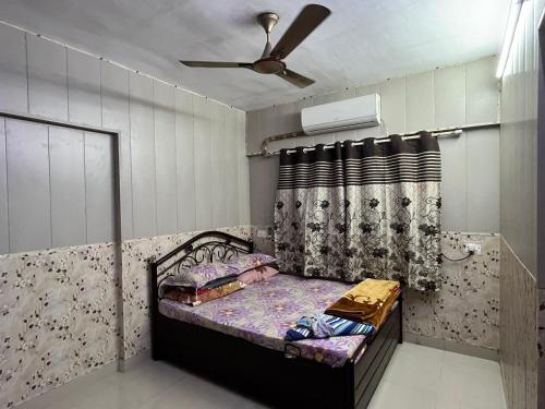 孟买Galaxy Apartment的一间带一张床和吊扇的小卧室