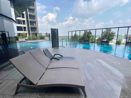 莎阿南Stylish Nordic Suite, Pool View, GEO Bukit Rimau, Kota Kemuning的游泳池旁甲板上的长椅