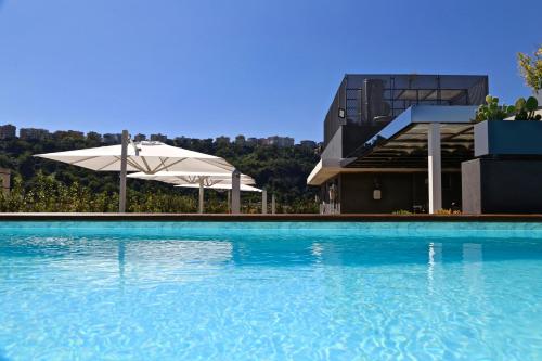 那不勒斯LHP Napoli Palace & SPA的一座带遮阳伞的游泳池以及一座建筑