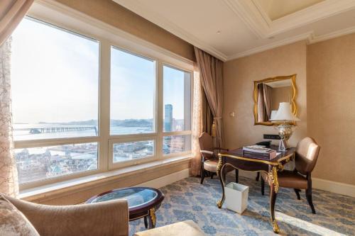 大连大连一方城堡豪华精选酒店的酒店客房设有一张书桌和一个大窗户。