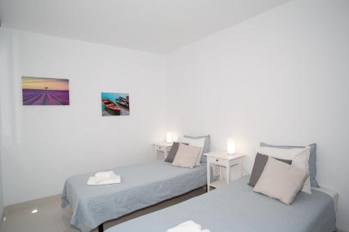 圣胡安海滩Casa Brillante的一间卧室配有两张床和一张带两盏灯的桌子。