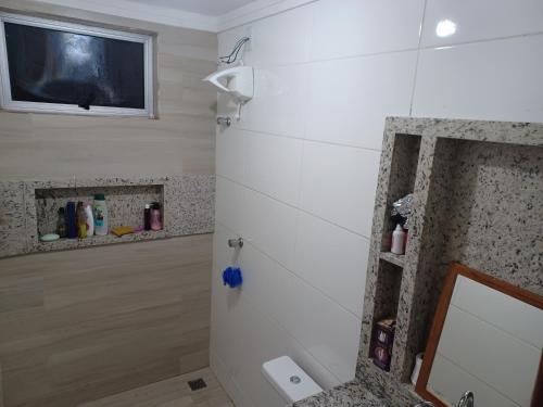 伊帕廷加Aluga-se quarto em apartamento的一间带镜子的浴室和墙上的电视