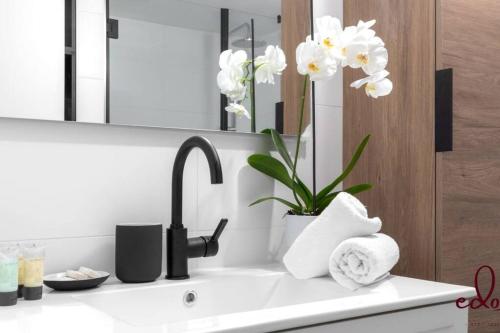 埃拉特דירה בסי סייד עם נוף מדהים לים - By Edom的浴室水槽设有镜子和白色的鲜花