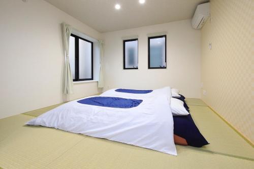 东京COTO Tokyo Sugamo的卧室配有一张白色大床和两个窗户