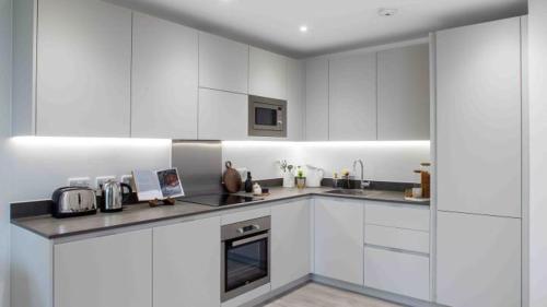 巴尔金Stylish Furnished Room In Barking Centre的厨房配有白色橱柜和炉灶烤箱。