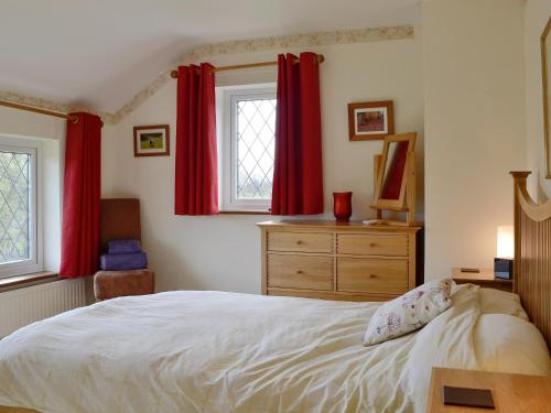 LydbrookOak Tree Cottage - E5062的一间卧室配有红色窗帘、一张床和一个梳妆台
