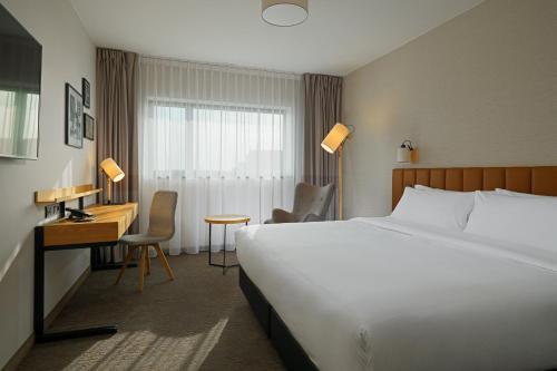 华沙Four Points by Sheraton Warsaw Mokotow的酒店的客房 - 带1张床、1张桌子、1张床和1张床
